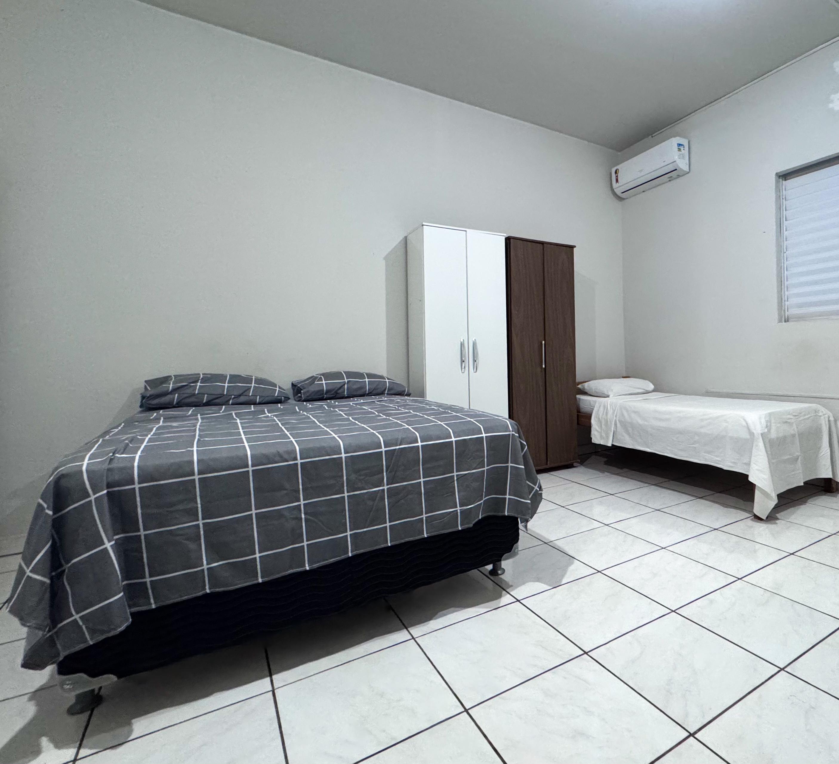 Quarto com cama de casal e cama de solteiro, com ar-condicionado